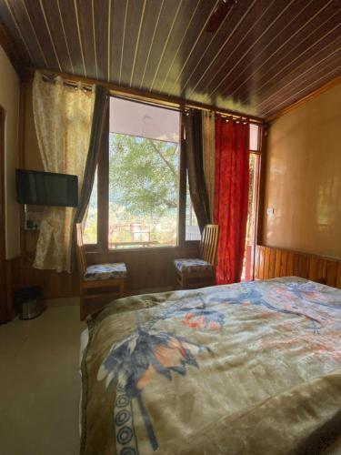 ein Schlafzimmer mit großem Bett und Fenster in der Unterkunft SAIRRA - Hotel & Restaurant in Manali