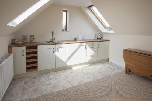 a kitchen with white cabinets and a sink in a attic at Genesta in Saint Minver