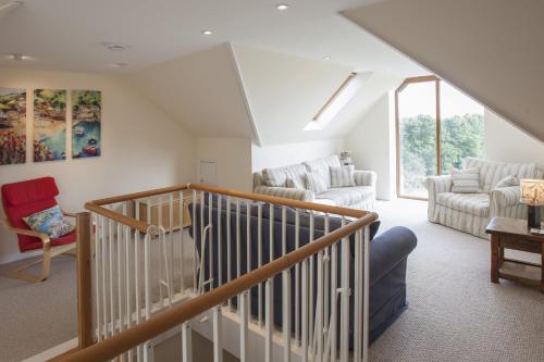 a living room with a staircase and a couch and chairs at Genesta in Saint Minver