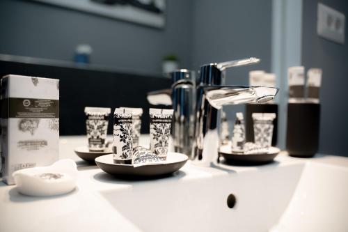 Un mostrador de baño con un lavabo con tazas y un grifo. en Luxury Down Town, en Bucarest