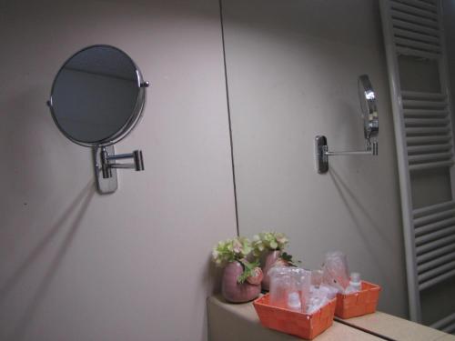a bathroom with a mirror and a table with flowers at BB La Bella Addormentata e il Principe Calaf in Lucca