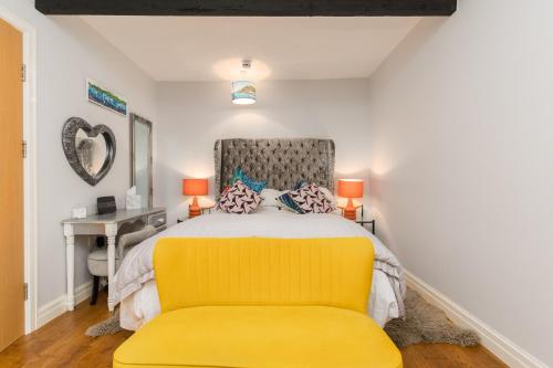 a bedroom with a yellow bed and a desk at No 31 Promenade APARTMENT by the sea in Aberystwyth