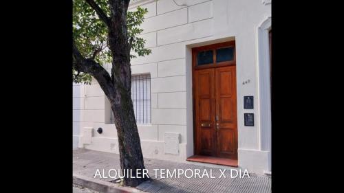 a building with a wooden door next to a tree at Acogedor departamento bien ubicado in Concordia