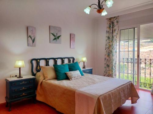 - une chambre avec un lit doté d'oreillers bleus et d'une fenêtre dans l'établissement Villa Azahar Anita, à Nerja