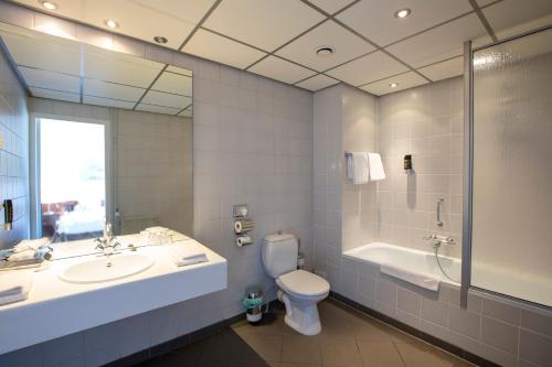 een badkamer met een wastafel, een toilet en een bad bij Hotel de Blaauwe Leeuw in Terneuzen