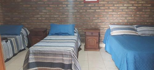 um quarto com 2 camas e uma parede de tijolos em Cabaña Las Brisas em Plottier