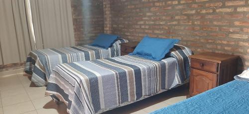 two beds in a room with a brick wall at Cabaña Las Brisas in Plottier