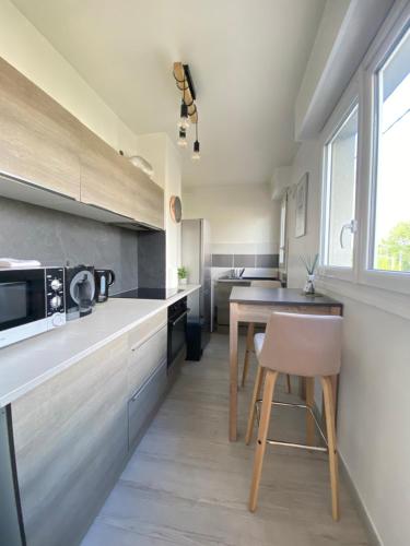 eine Küche mit einem Tisch und einer Mikrowelle in der Unterkunft COSY in Clermont-Ferrand