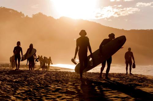 a group of people standing on a beach with surfboards at Reflections Seal Rocks - Holiday Park in Smiths Lake