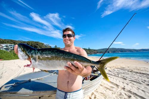 a man holding a fish on a beach at Reflections Seal Rocks - Holiday Park in Smiths Lake