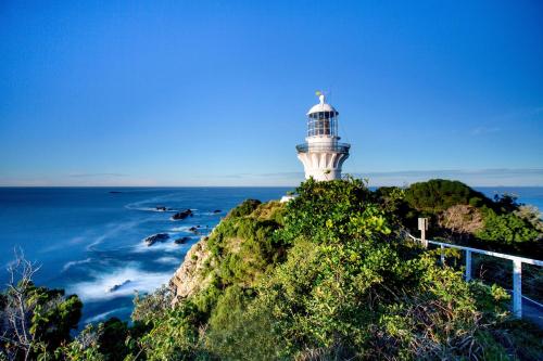 a lighthouse sitting on top of a hill next to the ocean at Reflections Seal Rocks - Holiday Park in Smiths Lake