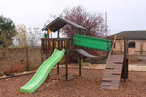 a playground with a green slide and a slideintend at Beautiful 4 Bedroom Cottage - Cottage 4 in Doncaster