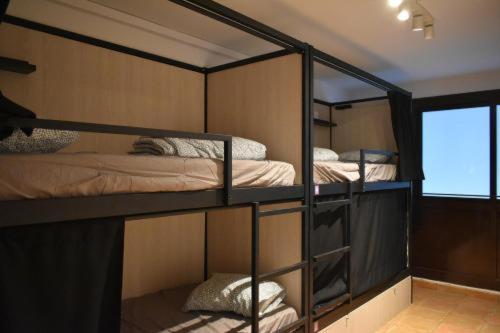 three bunk beds in a room with a window at Onefam Budapest in Budapest