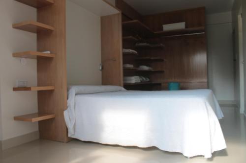 1 dormitorio con cama blanca y estanterías de madera en Departamento, zona centrica en Salta