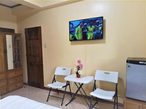 Habitación con mesa, sillas y TV en la pared. en Ocean Breeze Inn en Boracay