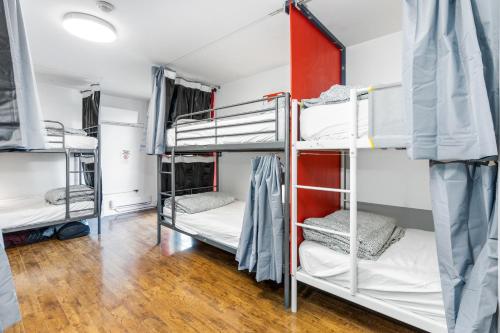 a room with three bunk beds and a wooden floor at Samesun Toronto in Toronto