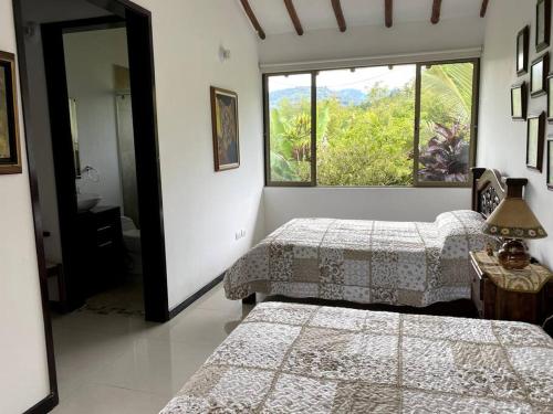 ラ・ベガにあるCasa ambiente rural La Vega Cundinamarcaのベッドルーム1室(ベッド2台、大きな窓付)