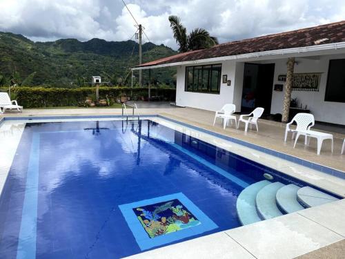 a large swimming pool with chairs and a house at Casa ambiente rural La Vega Cundinamarca in La Vega