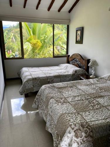 a bedroom with two beds and a large window at Casa ambiente rural La Vega Cundinamarca in La Vega