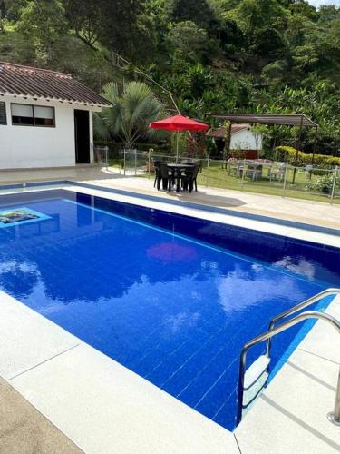 a blue swimming pool with a table and an umbrella at Casa ambiente rural La Vega Cundinamarca in La Vega