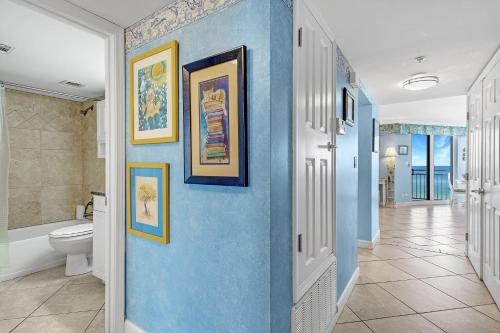 a bathroom with a blue wall with paintings on it at SeaSpray West 603- Gulf Front in Perdido Key