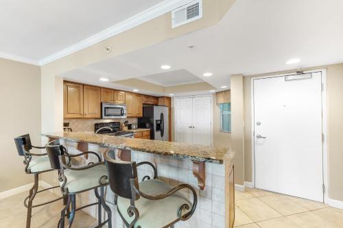a kitchen with a counter with stools in it at SeaSpray East 323- Gulf Front in Perdido Key