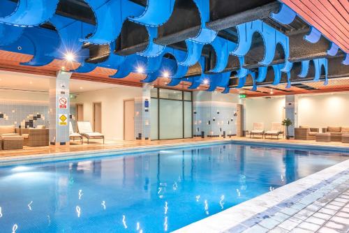 a swimming pool in a hotel with blue ceilings at Coppid Beech in Bracknell