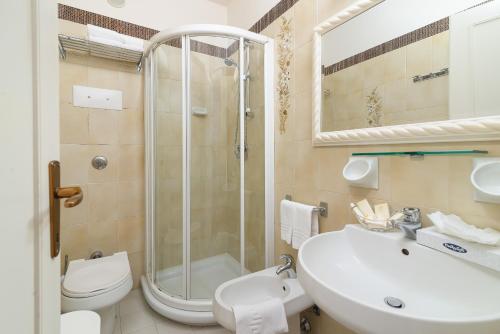 La salle de bains est pourvue d'une douche, d'un lavabo et de toilettes. dans l'établissement Universal Hotel, à Cervia