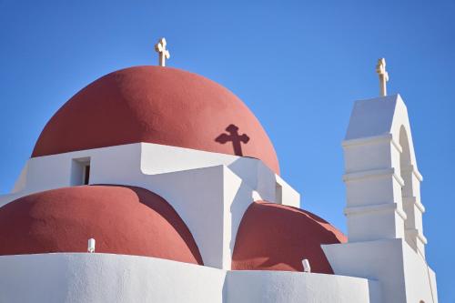 a red and white church with a cross on top at Once in Mykonos - Designed for Adults in Ornos