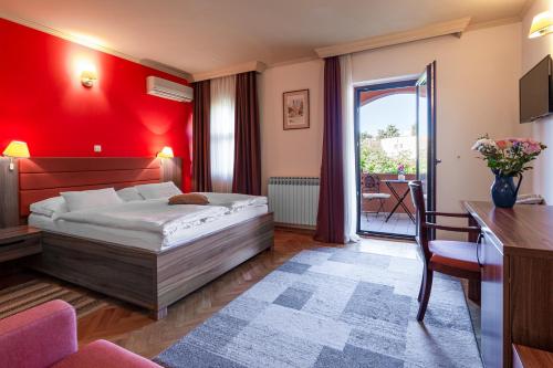 - une chambre avec un lit et un mur rouge dans l'établissement Hotel Marinko, à Zadar