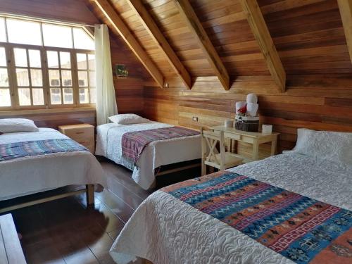 Zimmer mit 2 Betten und einem Schreibtisch in einer Hütte in der Unterkunft La Cabaña de Mari in Oxapampa