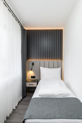 a bedroom with a white bed and a window at PARKHOTEL BRAUNAU - 24 Stunden Self Check-IN in Braunau am Inn