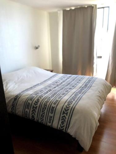 Un dormitorio con una cama con una manta. en Departamento vista al mar frente a playa El Sol, en Viña del Mar