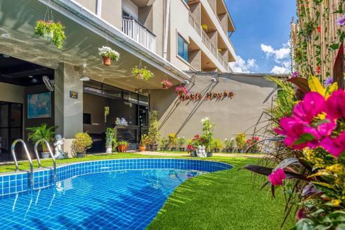 a swimming pool in the yard of a building with flowers at Noble House Patong in Patong Beach