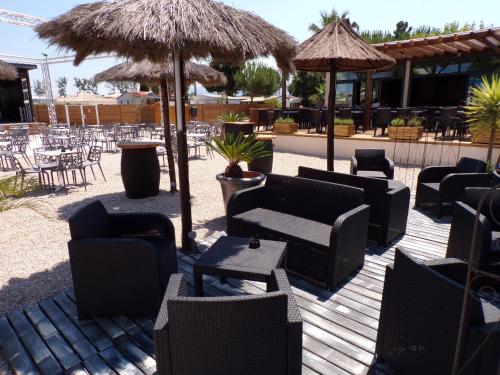 eine Terrasse mit Stühlen, Tischen und Sonnenschirmen in der Unterkunft Sun Sea camping le Bosc in Saint-Cyprien