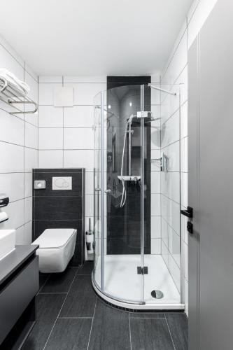 a bathroom with a shower and a toilet and a sink at PARKHOTEL BRAUNAU - 24 Stunden Self Check-IN in Braunau am Inn