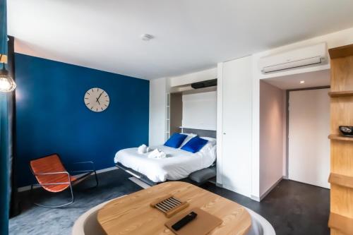 Cette chambre comprend un lit et une horloge murale. dans l'établissement L'Optimiste, Draps compris et Climatisation, à Sarlat-la-Canéda