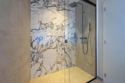 a shower in a bathroom with a marble wall at Ardn-bnb Bike n Bed in La-Roche-en-Ardenne