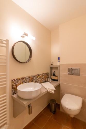 une salle de bain avec un lavabo, des toilettes et un miroir dans l'établissement L'Optimiste, Draps compris et Climatisation, à Sarlat-la-Canéda