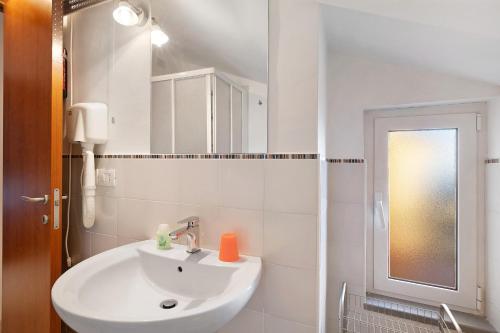 La salle de bains blanche est pourvue d'un lavabo et d'un miroir. dans l'établissement Casa Santi Appartamento Limone, à Giustenice