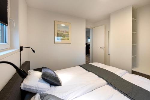 ein Schlafzimmer mit einem Bett mit weißer Bettwäsche und einer Lampe in der Unterkunft 95, gelegen aan het natuurmonument de Kampina in Oisterwijk