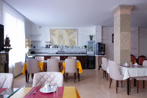 a dining room with tables and chairs and a kitchen at HOTEL ROYAL Paris Ivry in Ivry-sur-Seine