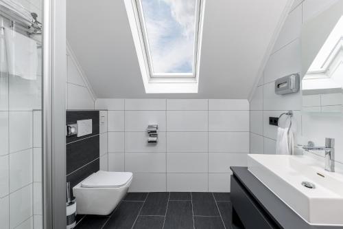 La salle de bains est pourvue de toilettes, d'un lavabo et d'une fenêtre. dans l'établissement PARKHOTEL BRAUNAU - 24 Stunden Self Check-IN, à Braunau am Inn