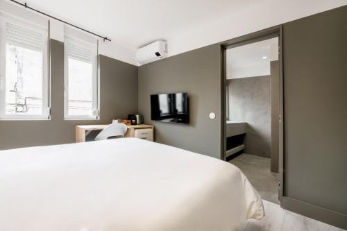 a bedroom with a white bed and a television at Rainbow Suites by Olala Homes in Cascais