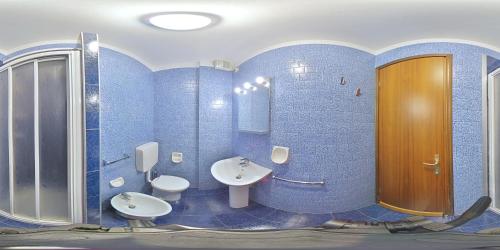 a blue bathroom with two sinks and two toilets at Salisburgo in Lignano Sabbiadoro