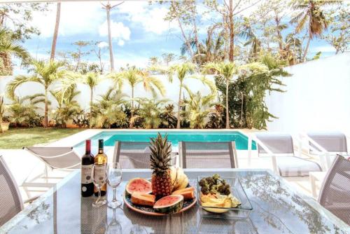 uma mesa de vidro com um prato de comida e vinho em 3 Bedroom Pool Villa 50M To The Beach em Las Terrenas