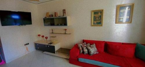 a living room with a red couch and a tv at Appartement haut standing a louer Petit déjeuner inclu in Tangier