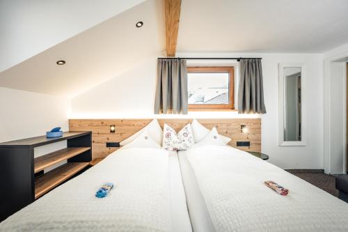 ein Schlafzimmer mit einem großen weißen Bett mit Schuhen drauf in der Unterkunft Pension der Steinbock - das 300 Jahre alte Bauernhaus - TIROL in Sankt Anton am Arlberg