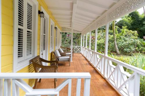 a porch of a yellow house with chairs and windows at Fond Doux Eco Resort in Soufrière