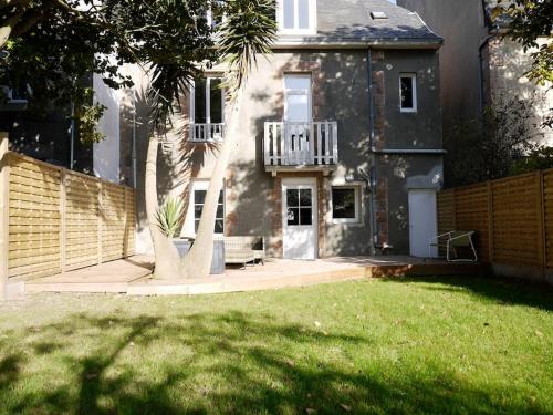 une maison avec une clôture et une cour avec de l'herbe verte dans l'établissement CLINT HOUSE - Appartement "Jardin de granit rose", à Perros-Guirec